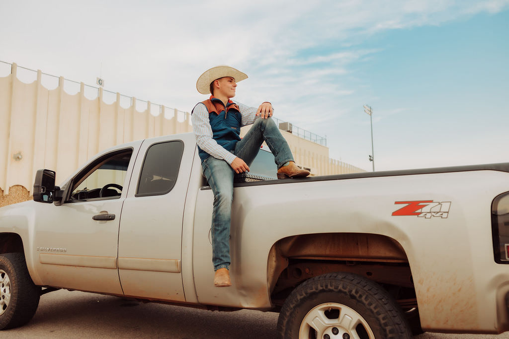 A high school boy sitting on top of his truck