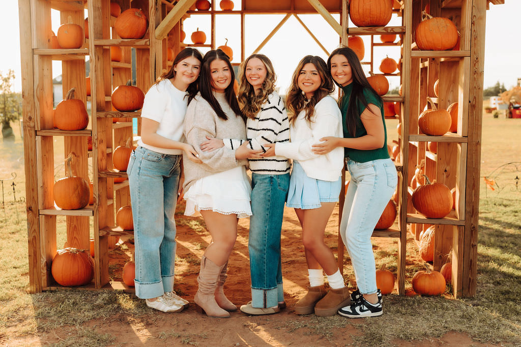 Five senior girls hugging for a picture in front of a Pumpkin Stand in Altus, Oklahoma